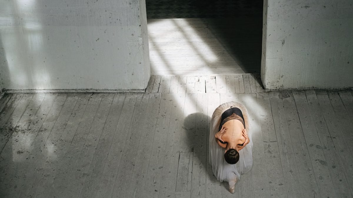 A ballerina performs a bow in an airy minimalist room, capturing grace and poise.